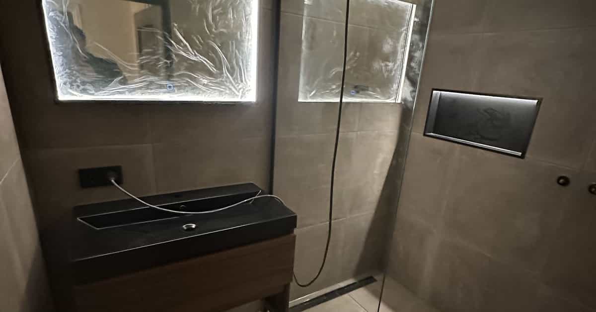 Finished bathroom with walk-in shower and illuminated mirror for the Vellema family in Drachten