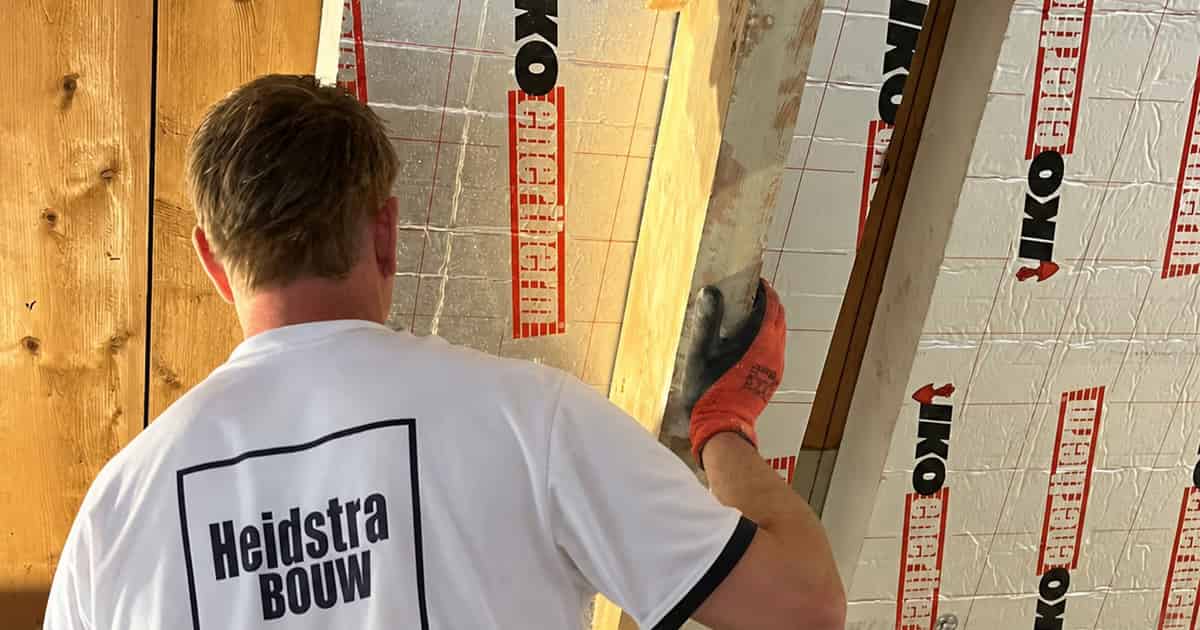 Medewerker van Heidstra Bouw plaatst isolatieplaten tegen het schuine dak aan de Dilgtweg in Haren