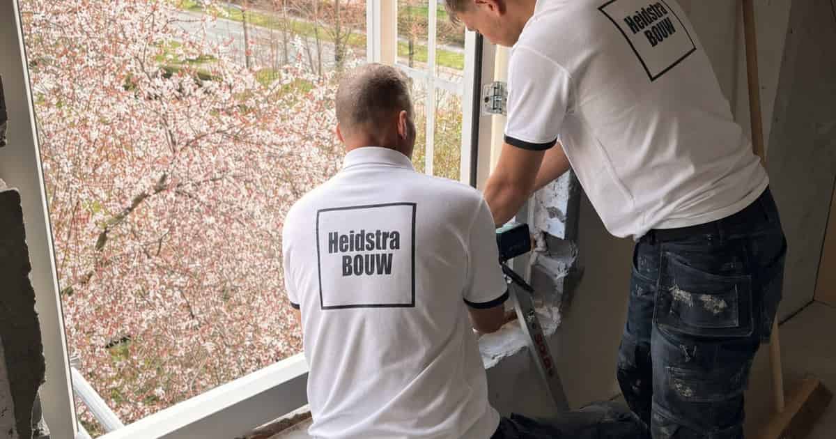 Medewerkers van Heidstra Bouw werken de aansluiting rond een raam af bij de woning aan de Dilgtweg in Haren